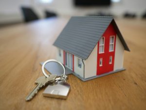Maqueta de casa y llaves, destacando beneficios de consultoría inmobiliaria.